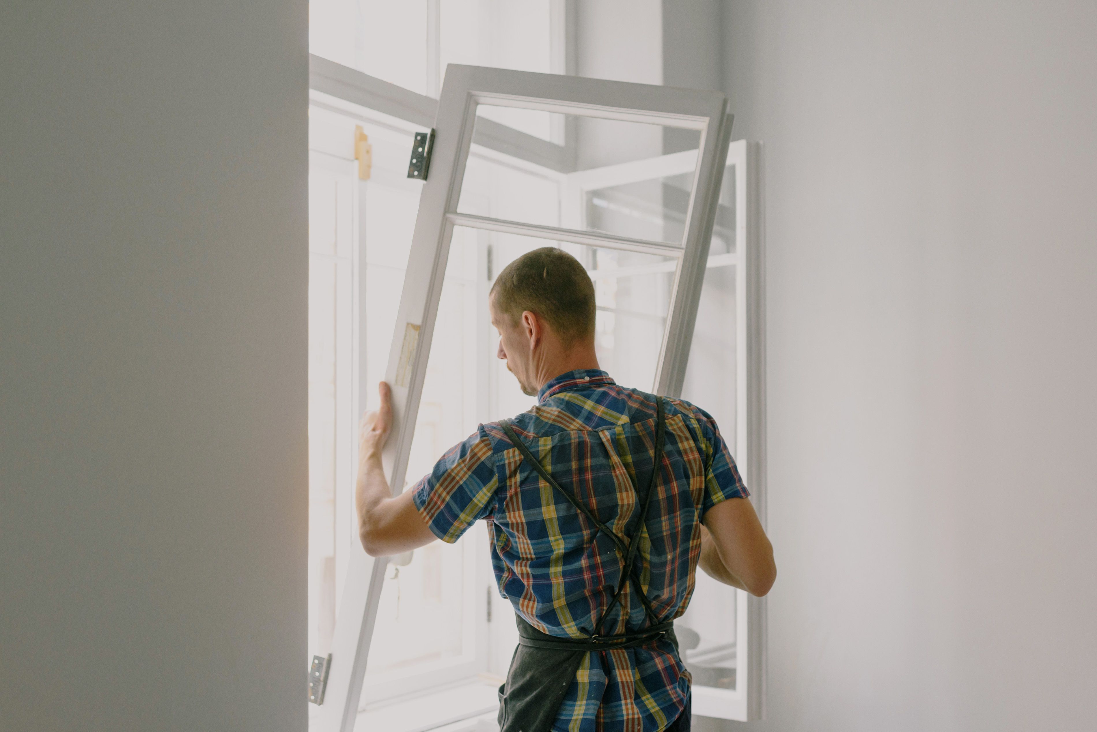 Professional installer fitting a replacement window inside a home